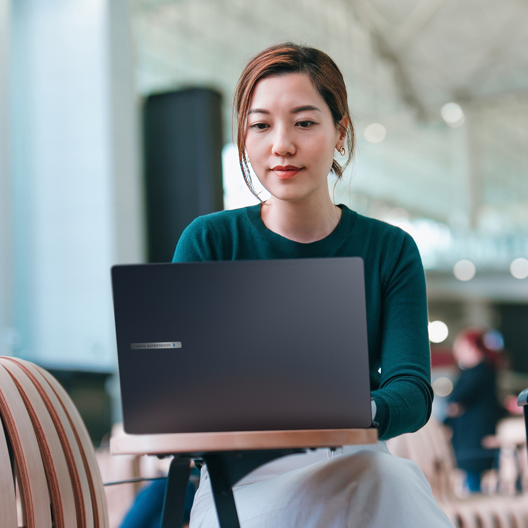 一位女性员工坐在机场咖啡厅里，使用 ASUS ExpertBook B 系列笔记本电脑